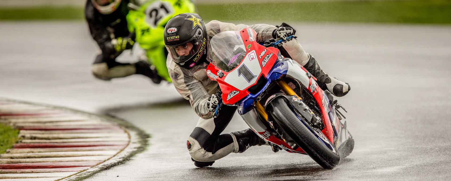 Andy DiBrino leaning hard into a turn at OMRRA round 1 at PIR in wet rainy conditions