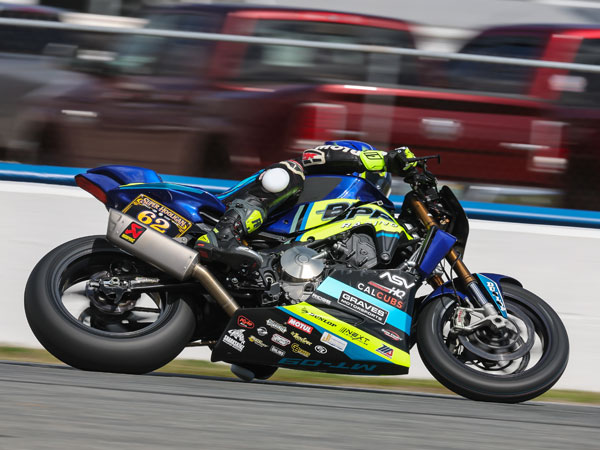 Andy DiBrino  leaning hard over on a knee and going fast around a turn at Daytona Super Hooligans