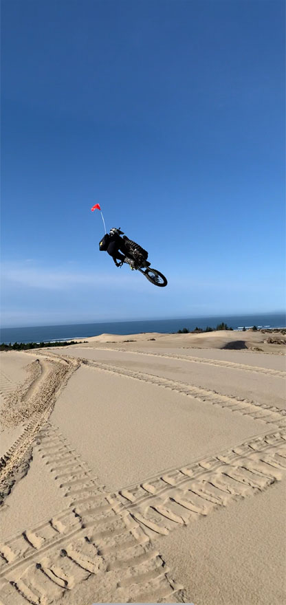 Andy flying at the Oregon Dunes Manchester Bay on the Pacific Coast on his dirt MX motorcycle with Pacific Coast and big sky all around him